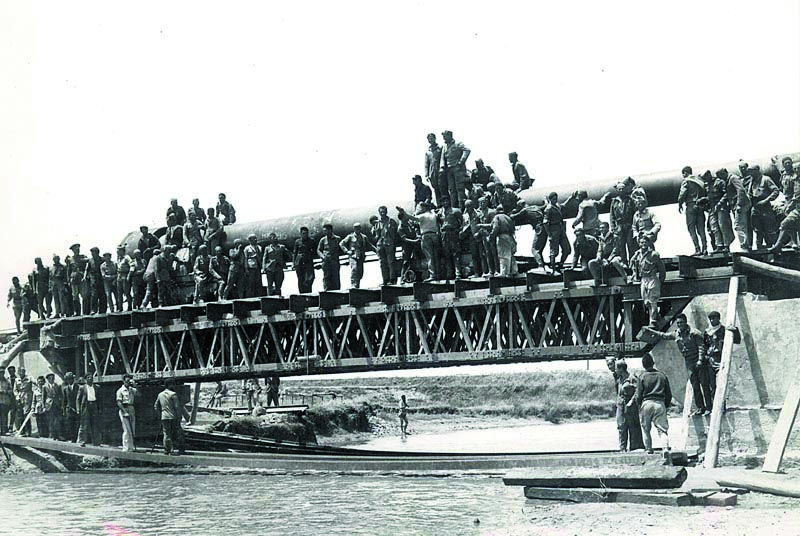 Trabajadores de los batallones de presos, algún mando militar y algún civil posan junto a un cañón de gran calibre sobre el recién construido puente del río Jara, en Tarifa. 