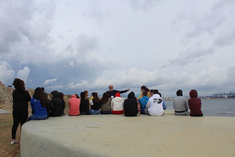 Alumnos de bachillerato, sentados sobre uno de los nidos de ametralladoras de la punta San García, con grúas del puerto de Algeciras al fondo.